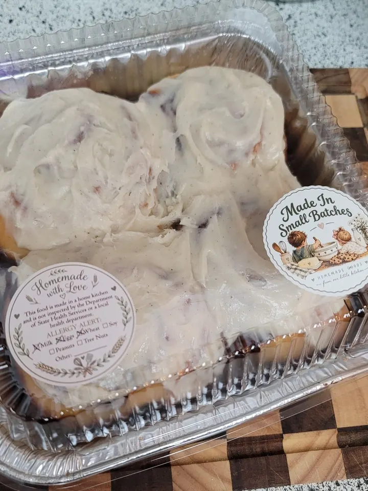 A four-pack of iced sourdough cinnamon rolls in a clear container