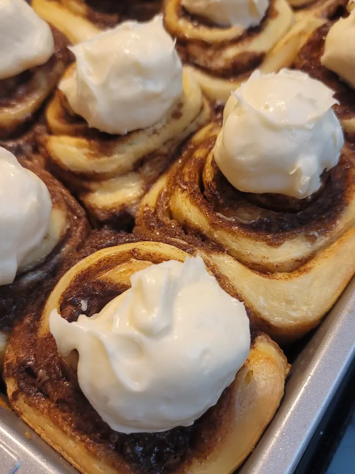 A pan of sourdough cinnamon rolls piled with cream cheese icing