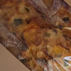 Jalapeño cheddar sourdough loaf with melted cheese pockets in a kraft sleeve
