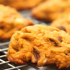 Soft orange pumpkin chocolate chip cookies on a cooling rack