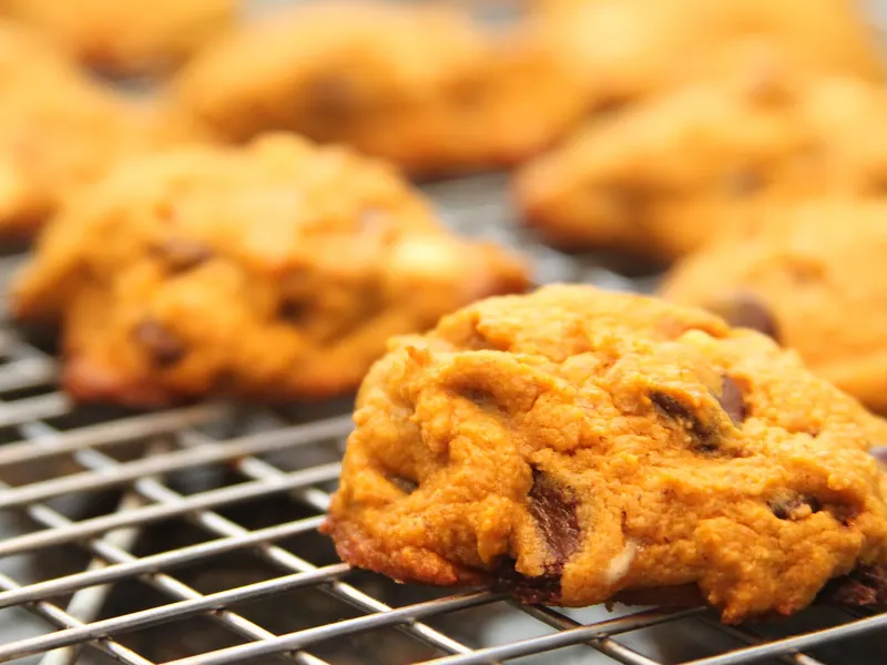Soft orange pumpkin chocolate chip cookies on a cooling rack